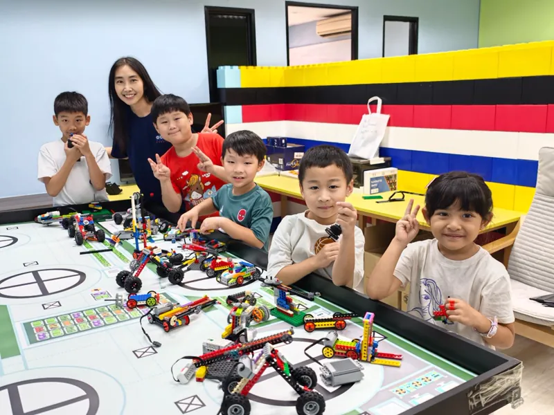 Children showing their robotics builds on a competition mat at a Meta Robotics holiday workshop